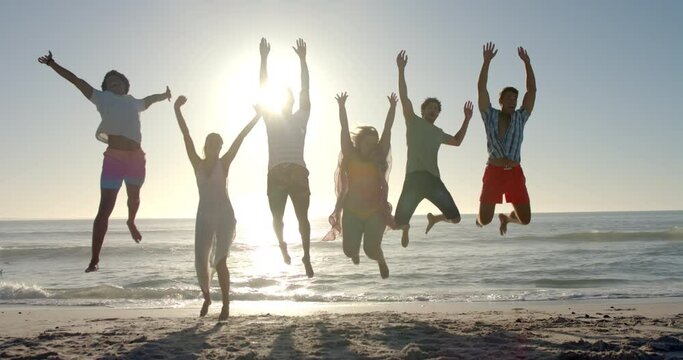 Diverse friends leap joyfully on a sunny beach