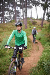 Naklejka premium Woman, bike and cycling outdoor on trail for exercise, workout or adventure in forest with fitness. People, cyclists and bicycle with helmet in woods or off road for sport, hobby and travel in nature