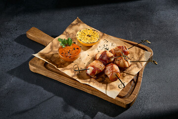 Chicken filet wrapped in bacon served on a rustic wooden board; a savory treat for meat lovers with a touch of finesse