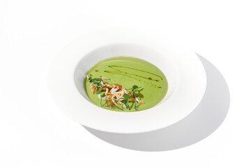 Spinach cream soup with squid garnished with herbs on white, ideal for health food advertising and restaurant menus