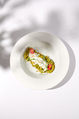 Spaghetti with Pesto Sauce and Stracciatella Cheese, Top View with Shadow on White, Perfect for Light and Airy Culinary Themes