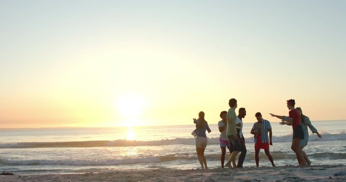 Diverse friends enjoy a beach at sunset, with copy space