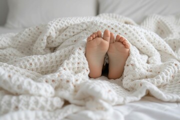 Comfortable barefoot gesture with human feet peeking out of white bed linen