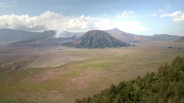 the rustic charm of the rugged valley and iconic Mount Bromo, an active volcano in Indonesia. Breathtaking views captured from the hill. aeria 4k drone footage