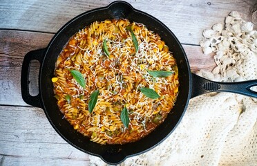 Fusilli  pasta in tomato sauce with  cheese  decorated with parsley on a wooden background