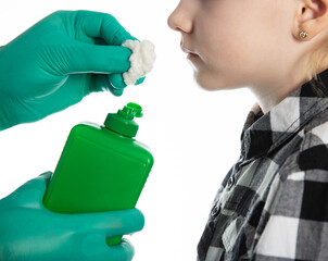 a doctor's hand in a medical glove holds a cotton swab with ammonia to the nose of a seven-year-old...