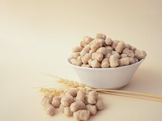 The extruded bran is poured into a white plate with a slide and spilled onto a beige background. A...