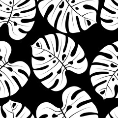 Seamless pattern with hand drawn tropical leaves on black background.