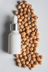Cosmetic product in tube, bottle, lotion or serumon chickpeas source on white background.