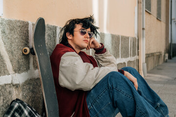 teenager with skateboard sitting on the street