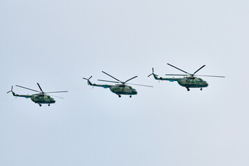 Three Russian military helicopters armed with missiles flies in blue sky, airborne mission of...