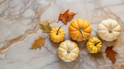 A group of pumpkins with dried autumn leaves and twig, on a light yellow color marble