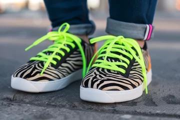 Fotobehang neongreen shoelaces on zebra print sneakers worn by a teenager © studioworkstock