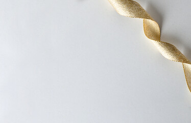 Golden ribbon in corkscrew in upper right corner on white
