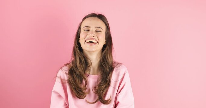 Happy joyful young woman wear pink sweater laughing out loud after hearing ridiculous anecdote, funny joke, feeling carefree amused, positive lifestyle, cover her mouth isolated on pink background