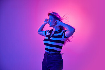 Gel portrait of attractive young woman smiling, posing in casual clothes against pink studio background in neon light. Happiness and joy. Concept of human emotions, youth, fashion, expression