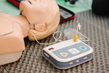 Automated external defibrillator device, AED with training dummy mannequin. Use an automatic defibrillator in conducting basic cardiopulmonary resuscitation of victim. Demonstrating chest compressions