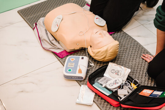 Automated external defibrillator device, AED with training dummy mannequin. Use an automatic defibrillator in conducting basic cardiopulmonary resuscitation of victim. Demonstrating chest compressions