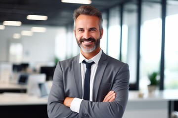 Confident male entrepreneur smiling while standing with arms crossed at office