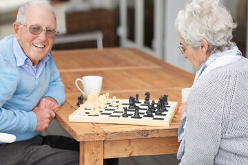 Happy, game and senior couple with chess together in retirement to relax on holiday or vacation. Elderly, man and woman outdoor with smile for winning competition, checkmate or activity with strategy