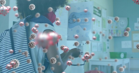 Multiple covid-19 cells floating against girl wearing face mask using hand sanitizer