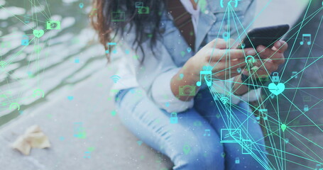 Image of network of connections over biracial woman using smartphone