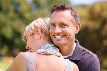 Fototapeta premium Love, couple and hug in nature with support, commitment and trust, care and solidarity while bonding in a park. Safety, security and people embrace in a garden with peace, calm or soulmate connection
