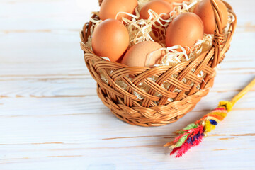 Eggs in a wicker basket on a white wooden table, copy space.