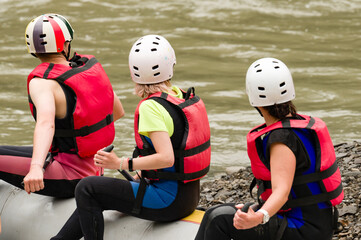 People are preparing for rafting. The athlete is waiting for the team on the bank of the river.