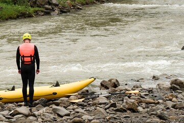 Man are preparing for rafting. The athlete is waiting for the team on the bank of the river.
