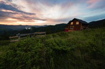 One house in the mountains, in the foreground a small windmill that generates electricity.