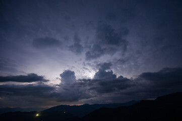 Evening thunderstorm with lightning in the mountains. Dramatic clouds during a thunderstorm pierce...
