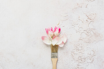 Ein Farbpinsel mit rosa Tulpen auf einem grauen Hintergrund. Flat lay.