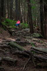 a woman sits on a fireplace near a path in the mountains.