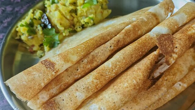 Closeup video of homemade crispy dosa with mashed potatoes served on a silver plate