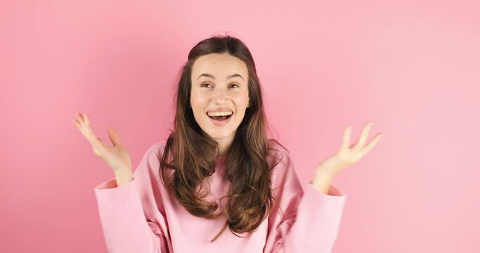 Happy woman open face, looking camera shocked surprised say wow cover mouth, spread hands. Wow, it is awesome. Surprised girl face. Shocked woman face expression isolated on pink background.