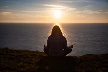 Deurstickers woman meditating by the sea at sunset © Melinda Nagy