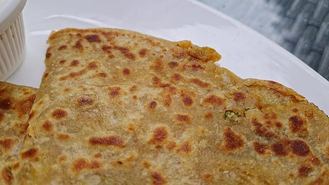 Pan shot of Indian famous food aloo paratha or flatbread served with yogurt and chutney