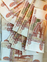 A lot of five-thousand-dollar bills are scattered on the table. Banknotes with a face value of 5000 rubles. Russian national currency