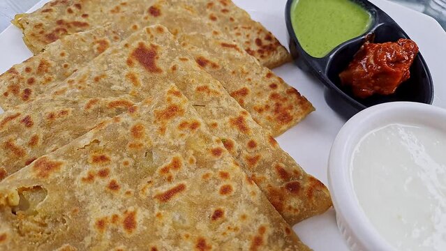 Pan shot of Indian famous food aloo paratha or flatbread served with yogurt and chutney