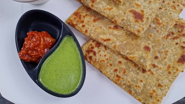 Pan shot of Indian famous food aloo paratha or flatbread served with yogurt and chutney