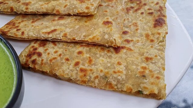 Pan shot of Indian famous food aloo paratha or flatbread served with yogurt and chutney