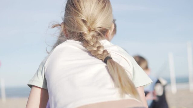  a girl with a thick long braid whispers in her friend's ear