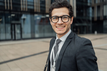 Smiling young businessman outside modern office building, corporate lifestyle.