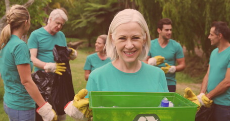 Image of happy diverse group picking up rubbish in countryside
