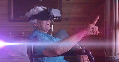 Image of light moving over senior woman in wheelchair using vr headset