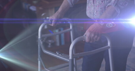 Image of light moving over midsection of senior woman using walking frame