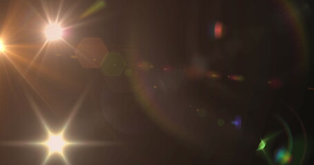 Image of spotlight with lens flare and light beams moving over dark background - Powered by Adobe