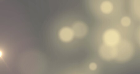 Image of bokeh white light spots moving over grey background