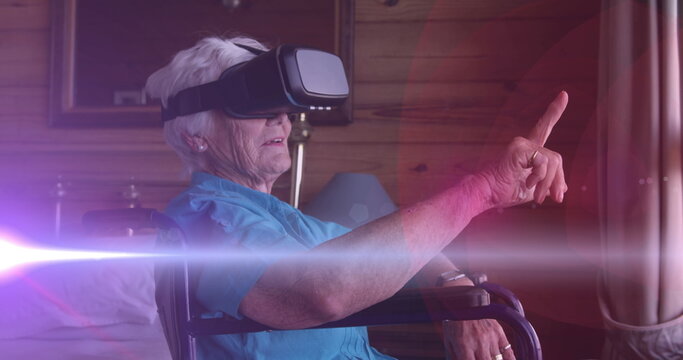 Image of light moving over senior woman in wheelchair using vr headset - Powered by Adobe